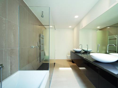 ein Badezimmer mit 2 Waschbecken, einer Dusche und einer Badewanne in der Unterkunft Apartement Blanc Harfa design in Prag