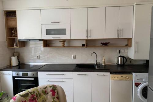 una cucina con mobili bianchi, un lavello e una stufa di Apartment Mona a Sarajevo