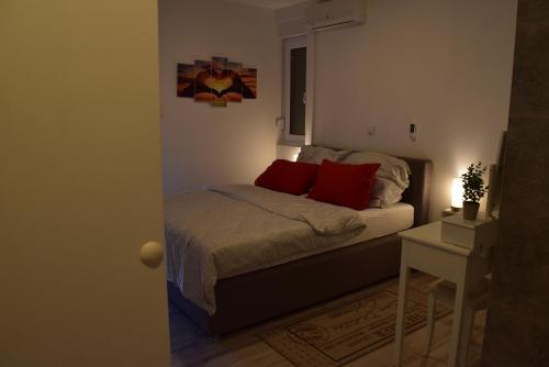 ein kleines Schlafzimmer mit einem Bett mit roten Kissen in der Unterkunft Savršen odmor u Villa Ivona in Zadar