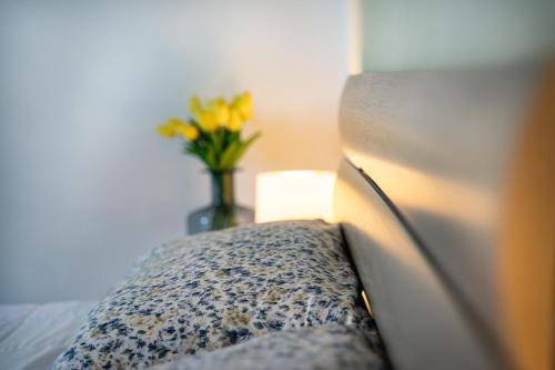 a bed with a vase of flowers on a table at Casa Tina Holiday Home in Diano dʼAlba