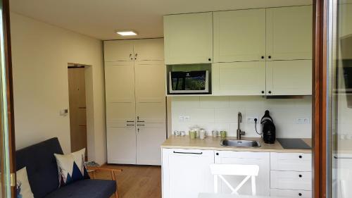 una cocina con armarios blancos y fregadero en Apartment No.35 en Vysoke Tatry - Horny Smokovec