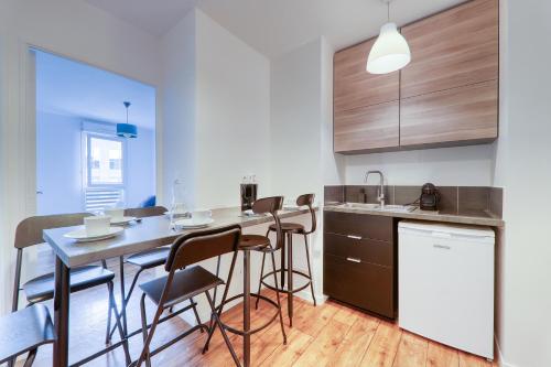 une cuisine avec une table et des tabourets de bar dans l'établissement Apartment Virtuose - Disneyland Paris 5min - Train station 250m, à Montévrain