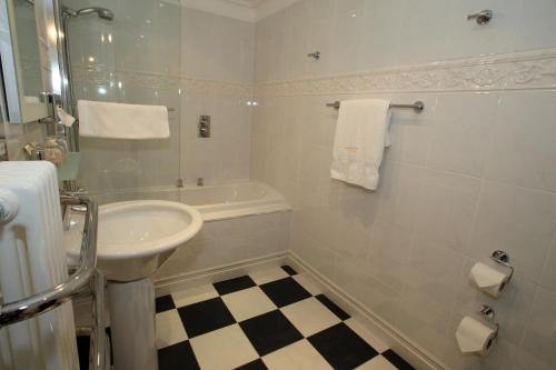 a white bathroom with a sink and a bath tub at Mansion House Hotel in Elgin
