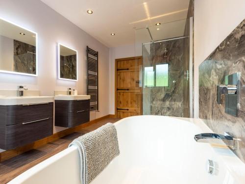 a bathroom with a tub and two sinks and a shower at Granar in Derwen