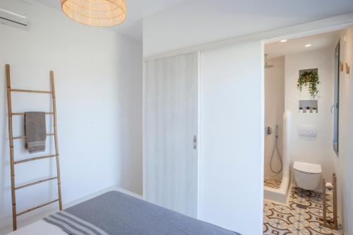 a bedroom with white walls and a bed and a bathroom at Olive White Villa in Hanioti