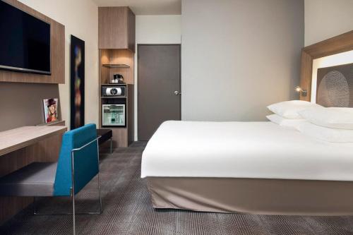 a hotel room with a large bed and a desk at Novotel Paris Rueil Malmaison in Rueil-Malmaison