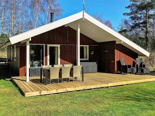 una casa con una terraza de madera con sillas en 4 person holiday home in L s en Læsø