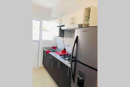 a kitchen with a black refrigerator and wooden cabinets at El hogar que deseas para vacacionar!!!! in Cancún