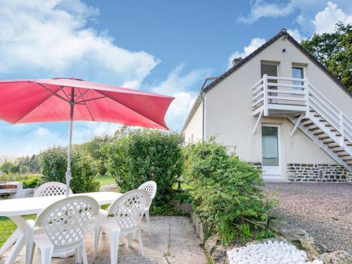 a table and chairs with a red umbrella and a house at Magnificent flat with garden in Saint R my in Clécy
