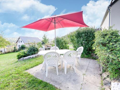 una sombrilla roja sobre una mesa y sillas blancas en Magnificent flat with garden in Saint R my en Clécy