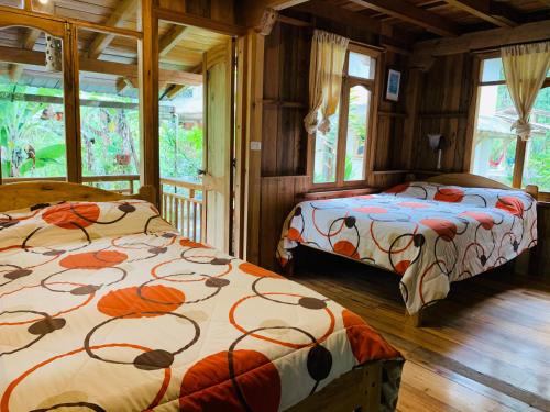 two beds in a room with windows at La Casa de Cecilia Mindo in Mindo