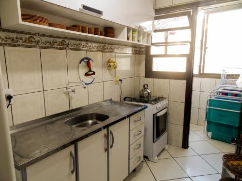 une petite cuisine avec un évier et une cuisinière dans l'établissement Apartamento Condomínio Mediterranée, à Capão da Canoa