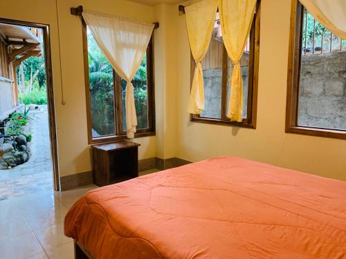 a bedroom with an orange bed and windows at La Casa de Cecilia Mindo in Mindo