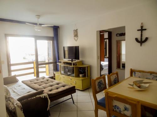 un salon avec un canapé, une télévision et une table dans l'établissement Apartamento Condomínio Mediterranée, à Capão da Canoa