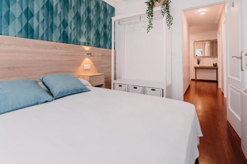 a bedroom with a white bed with blue pillows at PENSIÓN AUGAS QUENTES in Caldas de Reis