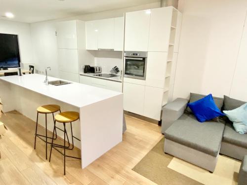 a kitchen with white cabinets and a counter and a couch at Large Townhouse 5 Beds with Two Parking Spaces - Manchester City Centre in Manchester