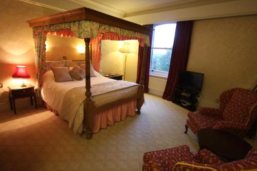Gipsy Hill Hotel في إكسيتير: غرفة نوم بسرير مظلة وكرسي