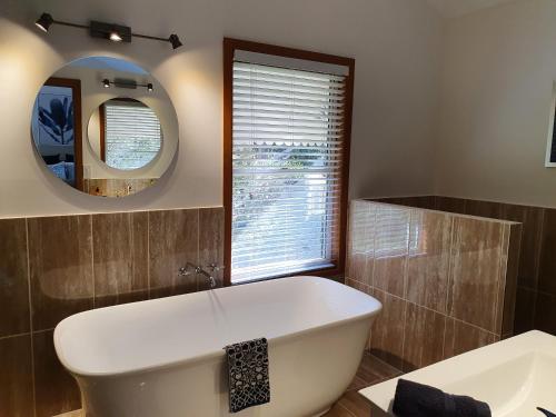 a bathroom with a large tub and a mirror at The Paddocks in Maleny