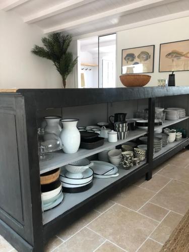 a shelf with dishes and vases on it at Belle villa rétaise 4 étoiles avec piscine chauffée in La Couarde-sur-Mer