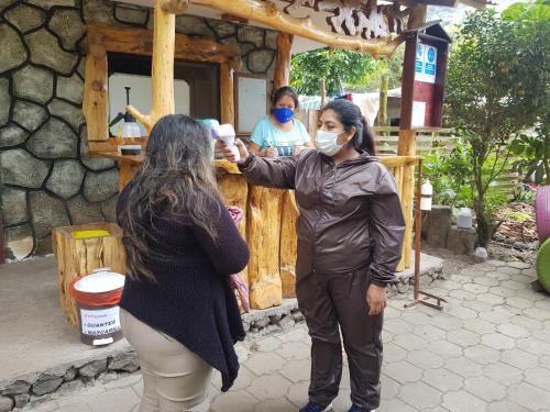 a woman wearing a face mask standing next to a woman wearing a mask at Ricky's House in Baños