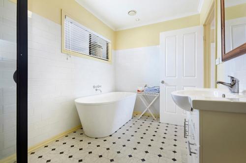 a white bathroom with a tub and a sink at Clifftop Apartments Portland Vic in Portland