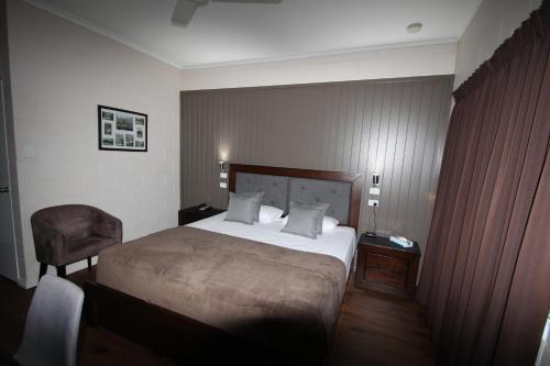 a hotel room with a bed and a chair at Colonial Rose Motel in Townsville