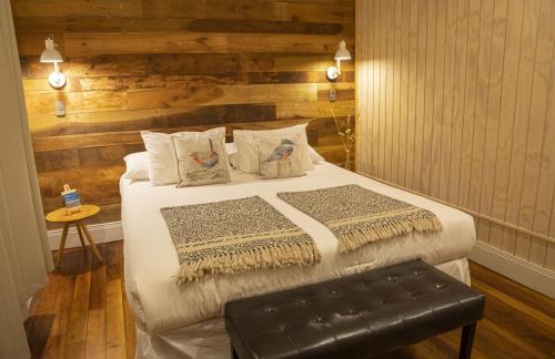 a bedroom with a bed with a bench in it at Hotel Nueve Ríos in Valdivia