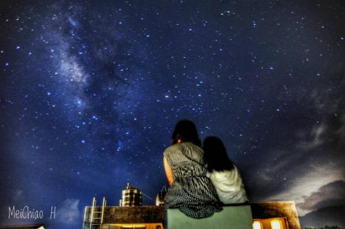 a couple sitting on a building looking at the stars at Taitung Crabs House in Chenggong