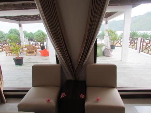 a room with two chairs and a large window at Friends Beach Hotel in Kuta Lombok
