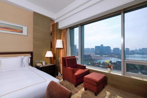 Habitación de hotel con cama, silla y ventana en Crowne Plaza Nanjing Jiangning, an IHG Hotel, en Nanjing