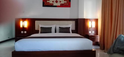 a bedroom with a large bed and two lamps at Friends Beach Hotel in Kuta Lombok