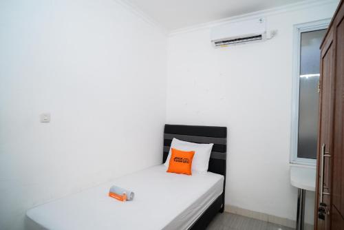 a small bedroom with a white bed with an orange pillow at KoolKost Syariah near Stasiun Rawa Buntu (Minimum Stay 6 Nights) in Tangerang
