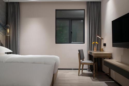 a hotel room with a bed and a desk and a window at Paco Hotel Jinfeng Metro Guangzhou-Free Shuttle Bus For Canton Fair-Self-service laundry in Guangzhou