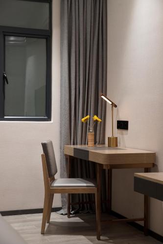 a desk with a lamp and a chair next to a window at Paco Hotel Jinfeng Metro Guangzhou-Free Shuttle Bus For Canton Fair-Self-service laundry in Guangzhou