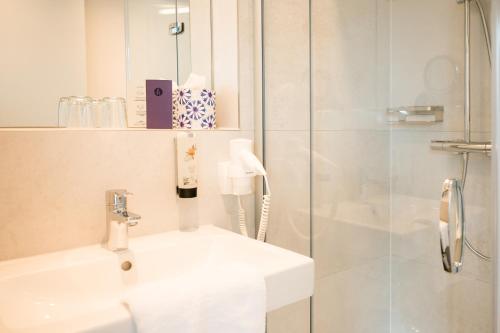 a white bathroom with a sink and a shower at HAIMHAUSERS Hotel Garni in Haimhausen