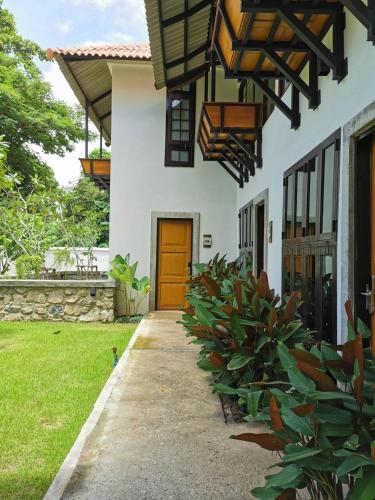 a white house with a brown door and some plants at Palin Family Cottage in Chiang Rai