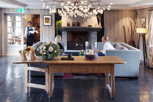 a living room with a table and a fireplace at Lysebu Hotel in Oslo