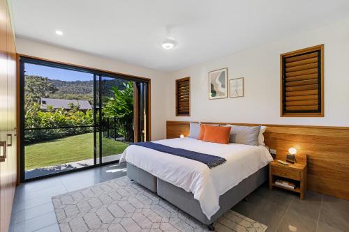 a bedroom with a large bed and a large window at Aqua - at Funnel bay in Airlie Beach