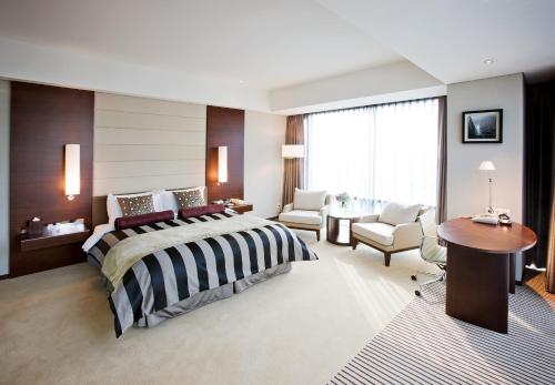 a bedroom with a bed and a table and chairs at Ramada Plaza by Wyndham Suwon in Suwon