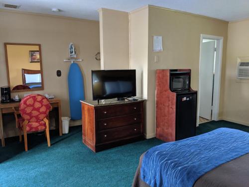 a hotel room with a bedroom with a bed and a television at Cheerio Inn - Glennville in Glennville