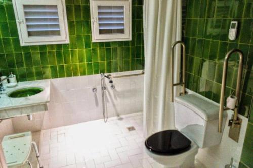a green tiled bathroom with a toilet and a sink at Casa del Príncipe in Daimiel