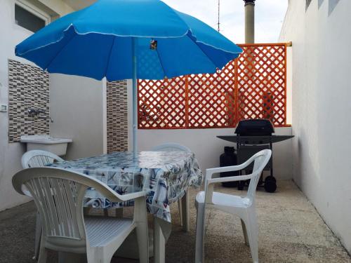 stół i dwa krzesła z niebieskim parasolem w obiekcie Appartamento Pompea w mieście Taviano