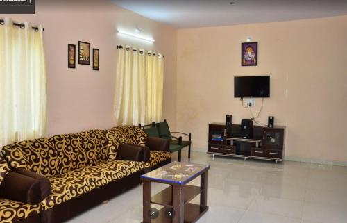 ein Wohnzimmer mit einem Sofa und einem TV in der Unterkunft Savitri bungalow 3BHK in Panchgani