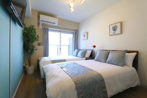 a bedroom with two beds and a window at Elizabeth Garden Shinsaibashi in Osaka