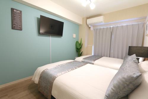 two beds in a room with a tv on the wall at Elizabeth Garden Shinsaibashi in Osaka