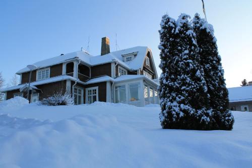 a house covered in snow with a tree at Trunna Vandrarhem & Konferens in Orsa