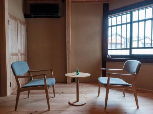 two chairs and a table in a room with a window at NIPPONIA HOTEL Yamefukushima Merchant Town in Ita