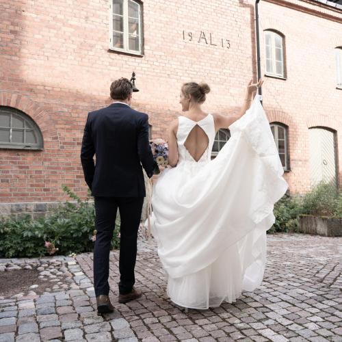 a bride and groom walking in front of a brick building at Botanika Uppsala in Uppsala