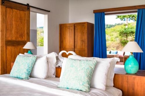 a bedroom with a bed with blue and white pillows at Villa Nambung in Selong Belanak