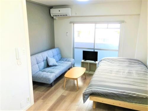 - une chambre avec un lit et un canapé bleu dans l'établissement Hotel Peace Park Tokaichi, à Hiroshima